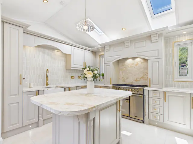 Modified Diamond show home kitchen with a rear-wall range cooker, quartz-topped island and gold fittings